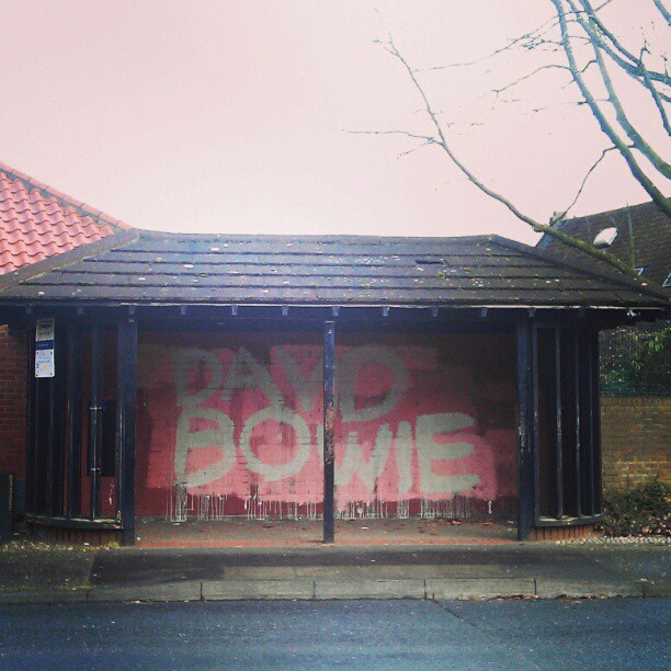 DAVID BOWIE in drippy white paint over pink and red in bus shelter
