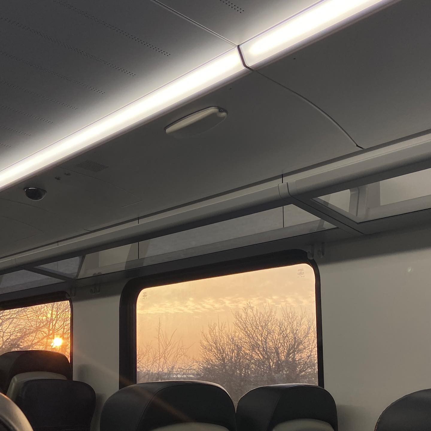sunset peeks in train window, warm light contrasting with cool internal beams