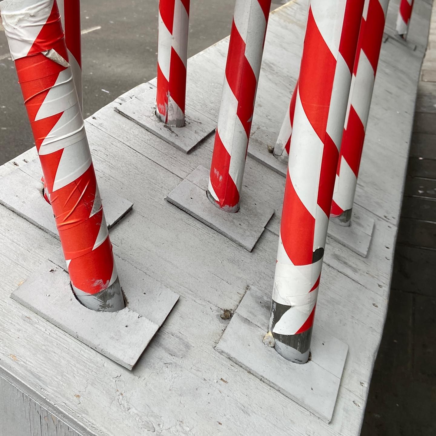 red and white scaffold stabs into wooden hoarding, over and over