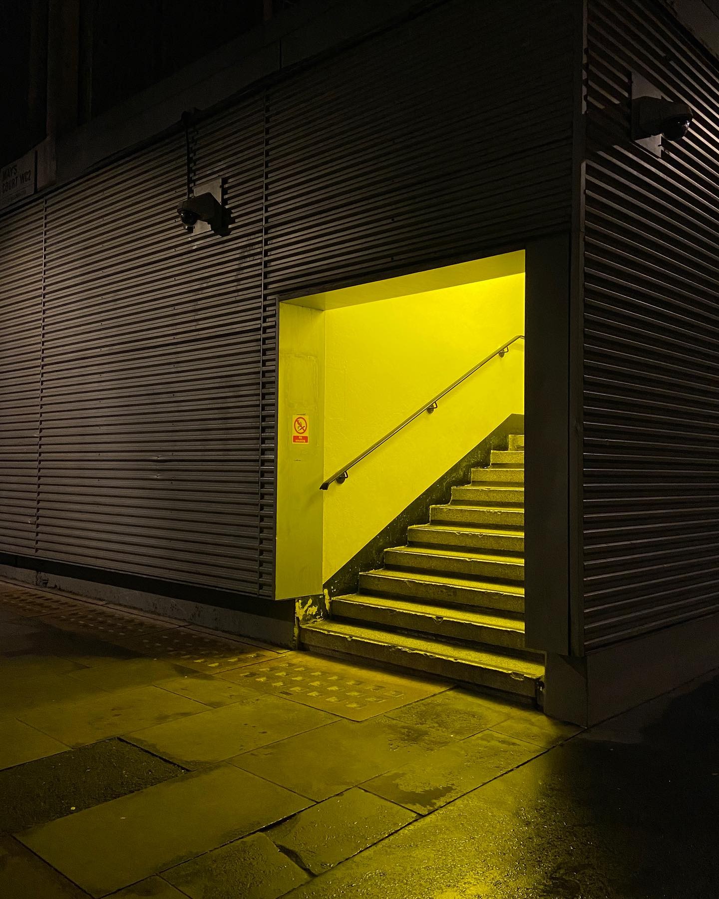 yellow glow spills out of parking structure after dark, stairs rising internally