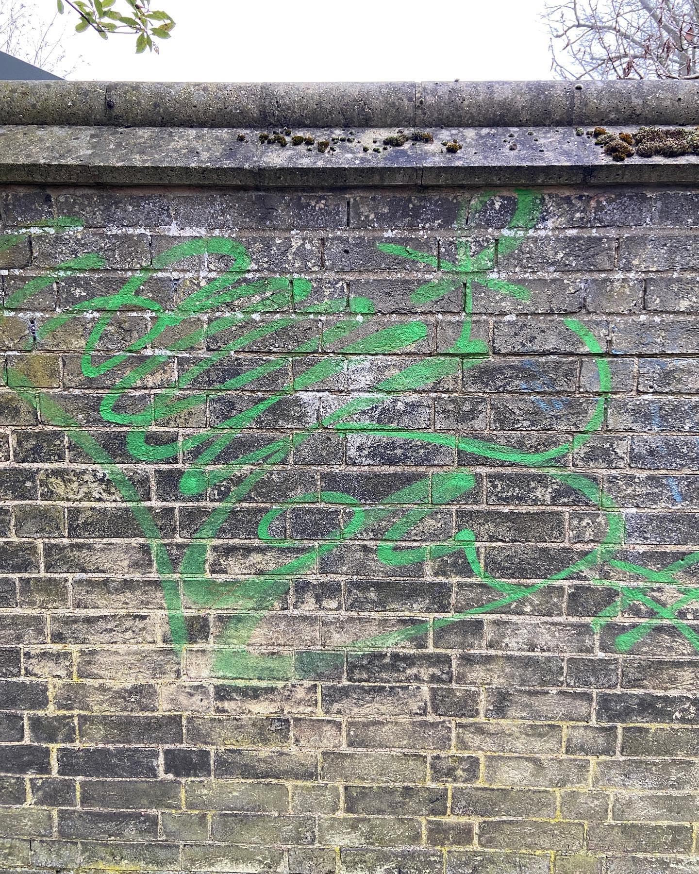 green scrawls on irregular grey and tan brick wall