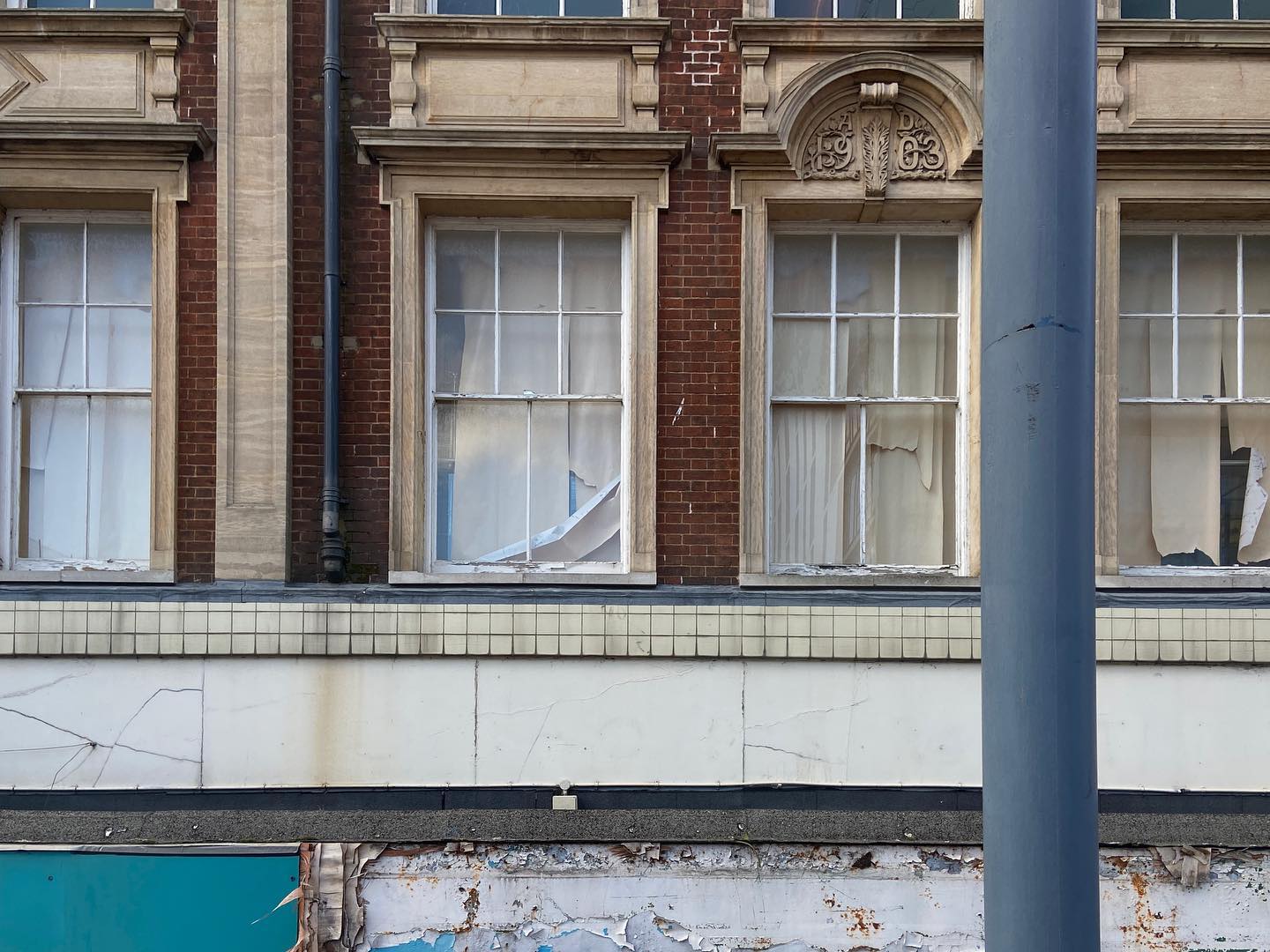 sash windows decay over falling frontage, grey pole interjects