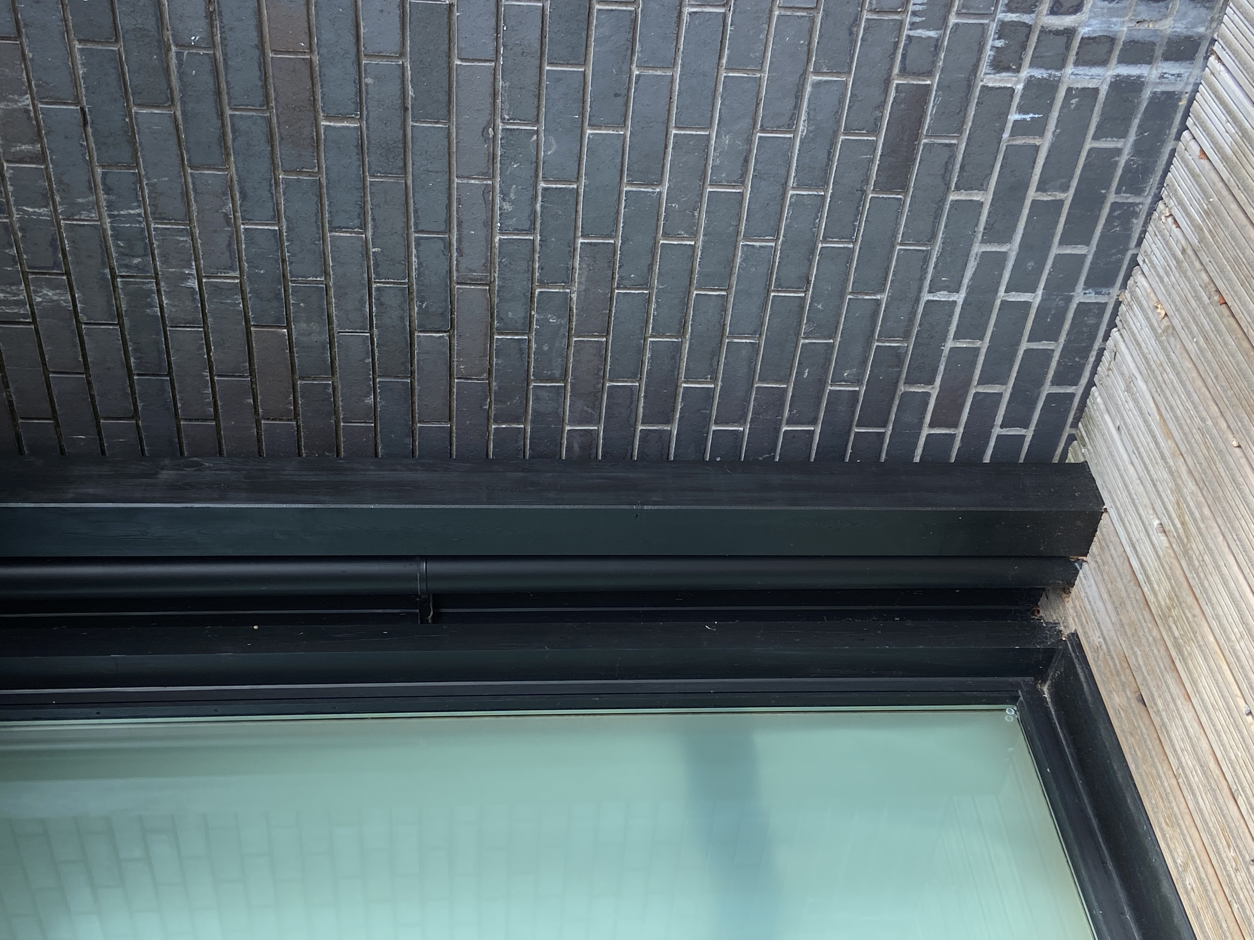 indoor/outdoor energy, glass pane to the left, black brick to the right. the floor is wooden